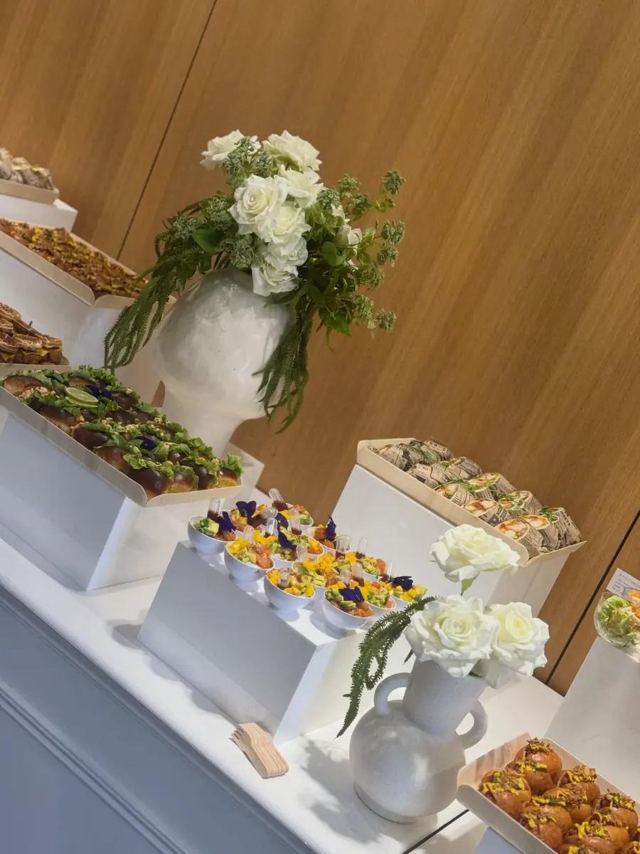 Buffet en intérieur avec présentoirs blancs, verrines et fleurs blanches